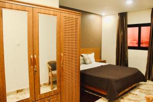 a bedroom with a bed and a wooden cabinet at CasaHouse Apparts in Nouakchott +31 photos