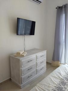 a bedroom with a dresser with a tv on the wall at Carlota Guest House in Cozumel