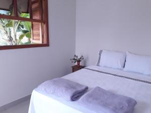 a bedroom with a white bed with two pillows on it at Suites Cerrado in Alto Paraíso de Goiás