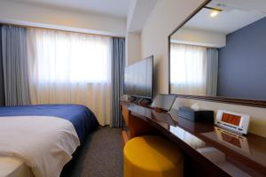 福岡市にあるホテルグランドルチェ博多のベッドと鏡が備わるホテルルーム