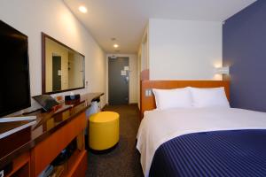 福岡市にあるホテルグランドルチェ博多のベッド1台、薄型テレビが備わるホテルルームです。