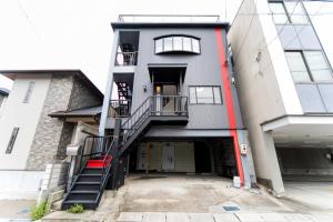 a building with a stairway leading into a parking lot at 7 min to JR Yokkaichi STN Large House in Yokkaichi