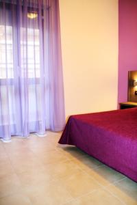 1 dormitorio con cama morada y ventana en Hotel Leon D'Oro, en Castelfrentano