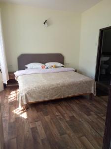 Green Tara Residency في دارجيلنغ: سرير في غرفة نوم مع أرضية خشبية
