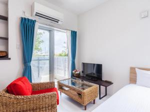 a bedroom with a bed and a tv and a chair at Little Island Okinawa Nago in Nago