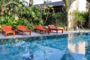 4 sillas sentadas junto a una piscina en La Paloma Resort, en Phu Quoc