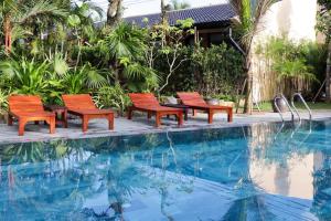 quatro cadeiras sentadas ao lado de uma piscina em La Paloma Resort em Duong Dong