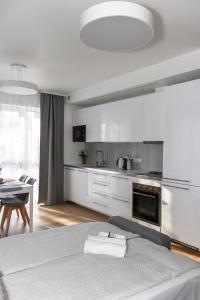 a white kitchen with a bed and a table at Krėvos apartamentai in Kaunas