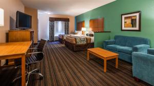 a hotel room with a bed and a living room at Best Western Plus Seminole Hotel & Suites in Seminole
