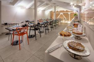 uma sala com mesas e cadeiras com comida em Best Western Plus Royal Superga Hotel em Cuneo