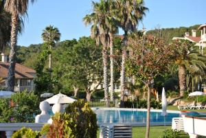 a pool in a resort with palm trees at HG Jardín de Menorca in Son Bou