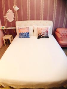 a bedroom with a white bed with pillows and a chair at Traveler Station R15 in Kaohsiung