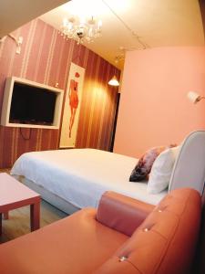 Cette chambre comprend deux lits, un canapé et une télévision. dans l'établissement Traveler Station R15, à Kaohsiung