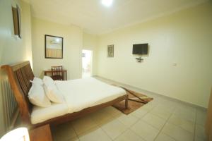 a bedroom with a bed and a tv on the wall at Entebbe Palm Hotel in Entebbe