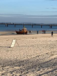 a boat on the beach with people walking and a pier at Useinseldom in Katschow