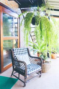 uma cadeira de vime sentada num alpendre com plantas em Wang Jai Kwang Space Inn em Chongsadao