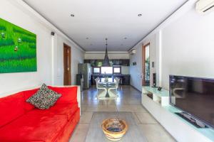 a living room with a red couch and a tv at AB Villa & Apartments in Seminyak
