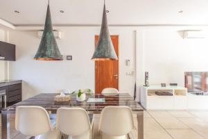 a kitchen with a dining room table with white chairs at AB Villa & Apartments in Seminyak