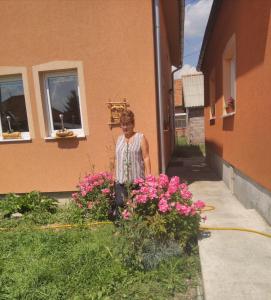 a woman standing next to a bunch of pink flowers at Apartmani ,,Bato,, in Sjenica