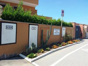 uma parede de retenção com plantas e flores numa rua em Camere Sul Mare em Ardea