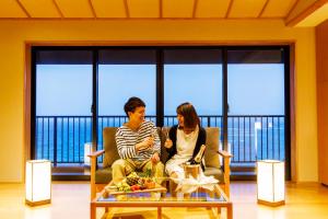 dwoje osób siedzących w fotelach w pokoju ze stołem w obiekcie Umino Ryotei Okinawa Nakamasou w mieście Onna