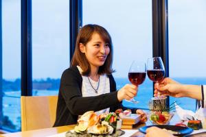 Umino Ryotei Okinawa Nakamasou في أونا: امرأة تجلس على طاولة مع كأسين من النبيذ