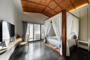 ein Schlafzimmer mit einem Himmelbett und einem TV in der Unterkunft 墾丁宜庭海景親子民宿 in Checheng