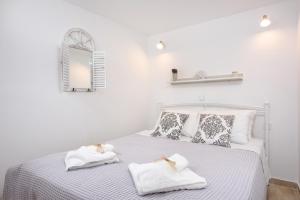 - une chambre blanche avec un lit et des serviettes dans l'établissement La vecchia bottega del Nonno - Corfu, à Corfou