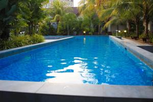 a swimming pool with blue water and palm trees at White Lodge in Pantai Cenang
