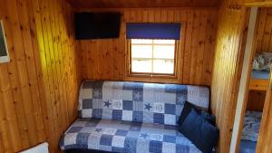 a bedroom in a log cabin with a bed in it at Helsingør Camping & Cottages Grønnehave in Helsingør