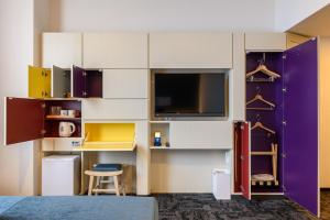 a room with a wall of cabinets and a tv at hotel MONday Premium TOYOSU in Tokyo