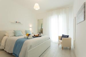 マリーナ・ディ・ラグーザにあるAcqua Azzurra Holiday Homeの白いベッドルーム(動物の詰め物が置かれたベッド付)