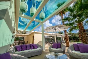 un patio con 2 sofás y una mesa con almohadas moradas en La Maison d'Ambrine - La Villa, en Chamaret