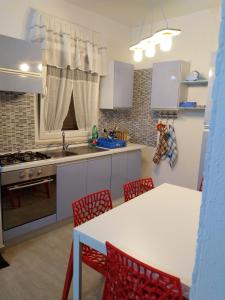 una cocina con sillas rojas y una mesa blanca en Rosa dei Venti house, en Campomarino