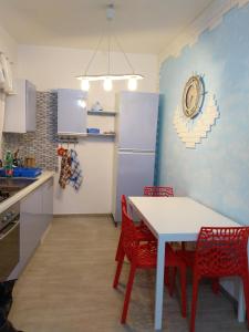 cocina con mesa blanca y sillas rojas en Rosa dei Venti house, en Campomarino