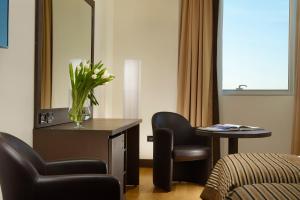 Habitación de hotel con escritorio, silla y espejo en Hotel Diamante en Alessandria