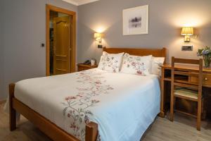 a bedroom with a bed and a desk and a bed sidx sidx sidx at Hotel Arco Navia in Navia