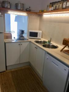 a small kitchen with a sink and a microwave at Es Cucó in Cala Galdana