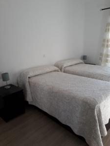 2 Betten in einem Zimmer mit weißen Wänden und Holzböden in der Unterkunft BenalBeach Yasmine in Benalmádena