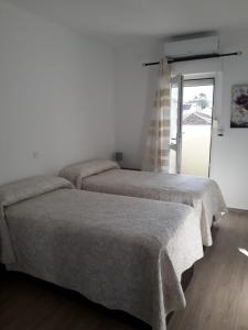 2 Betten in einem weißen Zimmer mit Fenster in der Unterkunft BenalBeach Yasmine in Benalmádena