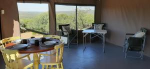 einen Tisch und Stühle in einem Zimmer mit einem großen Fenster in der Unterkunft Shamba Yetu Mountain Lodge in Maanhaarrand