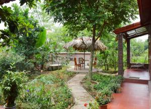 a patio with a table and a straw umbrella at Van Long Family Homestay in Ninh Binh