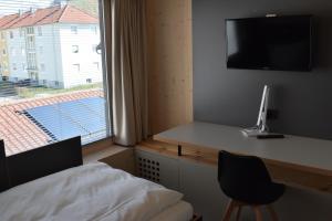 a bedroom with a bed and a desk with a television at NewAge Boardinghaus N70 in Heilbronn