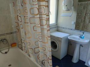 een badkamer met een douchegordijn en een wasmachine bij Apartman La Siesta in Bar