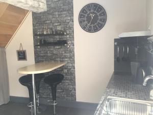 a bar with a clock on the wall and a table at Le Gite du Petit Lavoir in Bèze