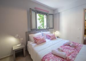 a bedroom with a large white bed with pink pillows at Ithaka Zante City Villa by "elite" in Zakynthos Town