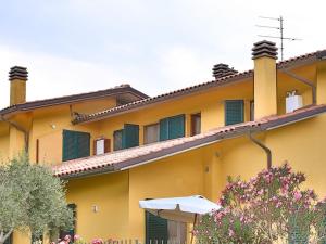 a yellow building with green shutters on it at Lago Trasimeno - Orione in Borghetto +5 photos