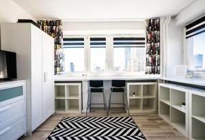 Elegant Apartment Panoramic في وارسو: مطبخ مع دواليب بيضاء وبار مع الكراسي