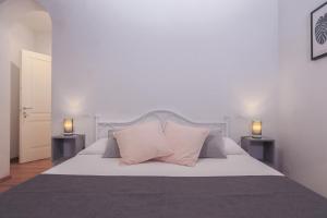 a bedroom with a white bed with two lamps at San Pierino Charming Rooms in Lucca