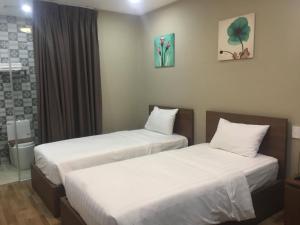 two beds in a hotel room with white sheets at Vic House Hotel in Da Nang